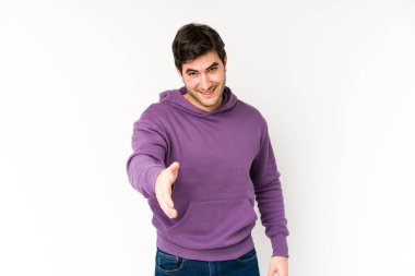 Beyaz arka planda izole edilmiş genç bir adam kameraya elini uzatarak selam veriyor..
