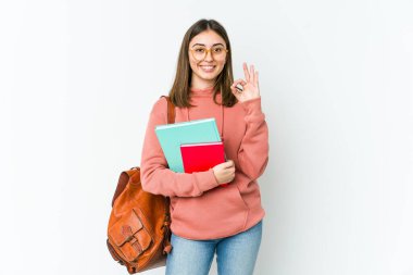 Beyaz fırında izole edilmiş, neşeli ve kendinden emin genç bir bayan iyi bir jest yapıyor..