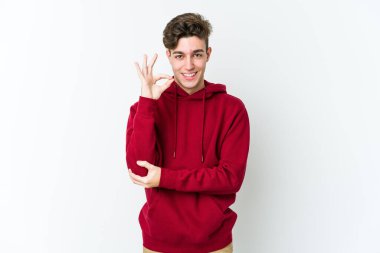 Beyaz arka planda izole edilmiş genç beyaz bir adam bir göz kırptı ve elleriyle iyi bir jest yaptı..