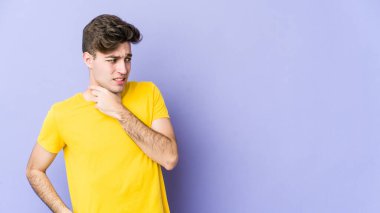 Kafkasyalı genç bir adam mor arka planda izole edilmiş kafasının arkasına dokunuyor, düşünüyor ve bir seçim yapıyor..