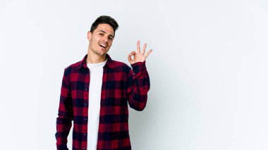 Beyaz arka planda izole edilmiş genç beyaz bir adam bir göz kırptı ve elleriyle iyi bir jest yaptı..