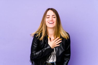 Mor arka planda soyutlanmış beyaz bir kadın yüksek sesle gülüyor ve elini göğsüne koyuyor..