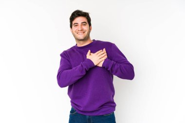Beyaz arka planda izole edilmiş genç bir adam, dostane bir ifadeye sahip, avuçlarını göğsüne bastırıyor. Aşk konsepti.