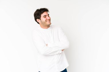 Beyaz arka planda izole edilmiş genç adam kollarını kavuşturarak gülümsüyor..