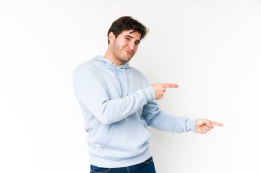 Beyaz arka planda izole edilmiş genç adam işaret parmaklarıyla fotokopi alanını işaret ederek heyecan ve arzuyu ifade ediyor..