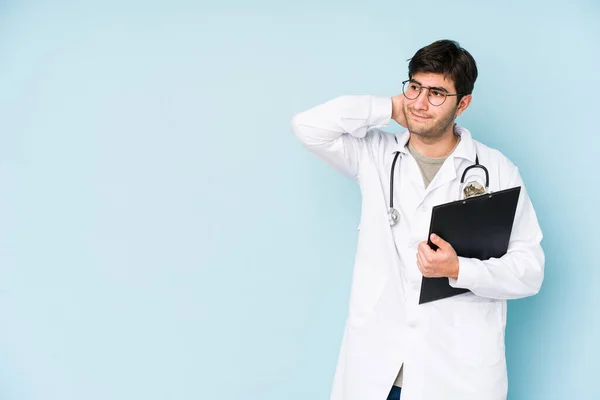 Ung Läkare Man Isolerad Blå Bakgrund Vidröra Baksidan Huvudet Tänka — Stockfoto