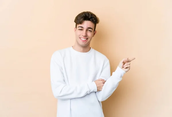 Young Caucasian Man Isolated Beige Background Smiling Cheerfully Pointing Forefinger — ストック写真