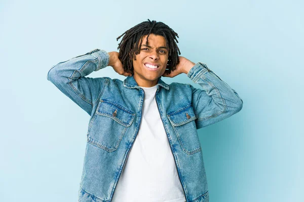 Young black man wearing a jeans jacket touching back of head, thinking and making a choice.