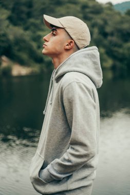 Bahar mevsiminde, ormanın ortasında bir gölde model olan genç bir çocuk..