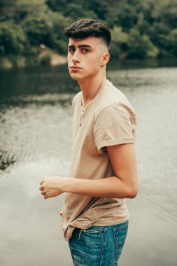 Bahar mevsiminde, ormanın ortasında bir gölde model olan genç bir çocuk..