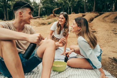 Bir grup genç arkadaş gölün ortasında piknikte bira içiyorlar..