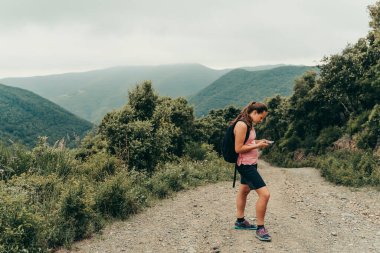 Doğa yürüyüşçüsü dağın tepesindeki bir cep telefonuna bakıyor..