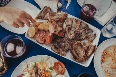 Yemek ve alkollü içeceklerle dolu mavi masa örtülü restoran masası..