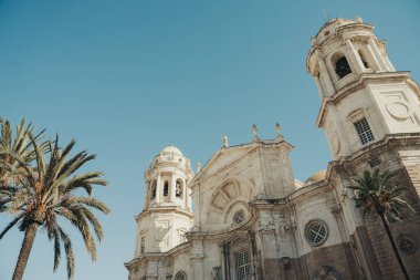 Güneşli ve açık bir günde palmiye ağaçları olan kilise, Cadiz, İspanya.