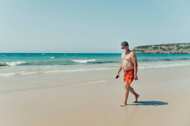50 yaşında güneş gözlüklü ve Endülüs, İspanya sahilindeki salgın için maske takan bir adam..