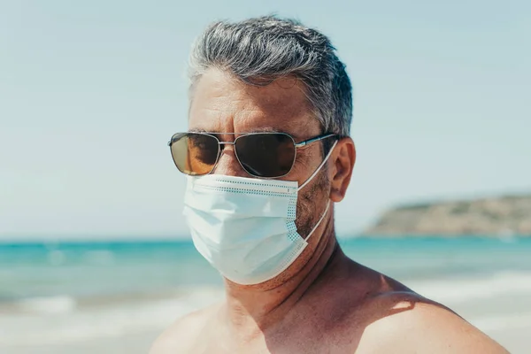 50-year-old man with sunglasses and a mask for the pandemic on the beach in Andalusia, Spain.
