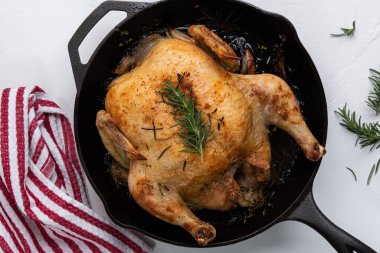 Biberiyeli kızarmış tavuk, kekik ve arpacık soğanı dökme demir tavada havluyla.