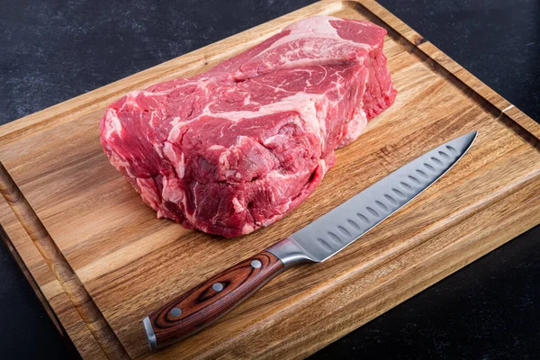 Boneless Beef Chuck Roast on a cutting board with a carving knife in the kitchen