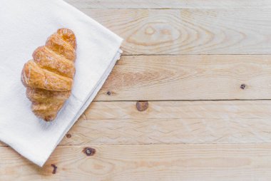 Üst görünüm beyaz kumaş üzerine taze kruvasan tahta masa arkaplanı ve kopyalama alanı