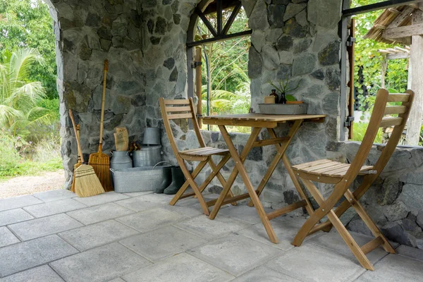 Empty wooden table and chairs with stone living room in the garden