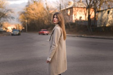 Şehir Yürüyüşü 'ndeki Şık Giyimli Kadın Portresi. Şehirde çekilen güzel bir kızla fotoşop. Profesyonel fotoşop: Paltolu ve şapkalı güzel bir kadın bahar (veya sonbahar) şehir sokaklarında yürüyor.