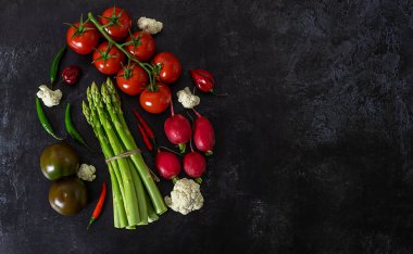 Siyah arka planda taze çiğ sebzelerin görüntüsü. Domates, biber, yeşil kuşkonmaz, turp, karnabahar. Düz yat, boşluğu kopyala