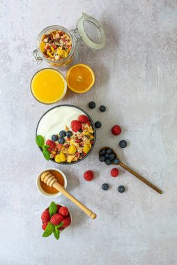 Dikey oryantasyon. Sağlıklı kahvaltı konsepti. Müsli, böğürtlen, bal ve taze sıkılmış portakal suyu. Üst görünüm, alanı kopyala