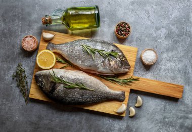 Baharatlı taze çiğ dorado balığı. Ahşap kesim tahtasının üzerinde pişirme veya ızgara malzemesi..