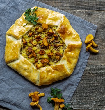 Altın chanterelle mantarı ve patatesten yapılmış fırınlanmış açık turta galetesinin üst görüntüsü. Kapat.