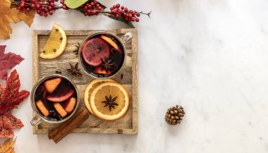 Baharatlı ve narenciyeli bardakta sıcak sonbahar şarabı. Üst manzara, mermer masadaki dekorasyonlar