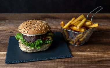 Kırmızı soğanlı ev yapımı sığır burger, fırında keçi peyniri ve ceviz. Buğday ekmeği. Kızarmış patatesle servis edilir..