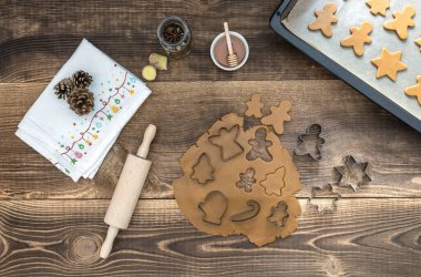 Noel kurabiyeleri için yuvarlanmış hamurla ahşap masada tatil süslemeleri.