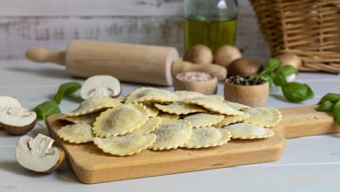 Taze çiğ İtalyan usulü makarna ravioli veya mantarlı tortelli, pesto ve ricotta. Ev yapımı yemek, vejetaryen tarifi..