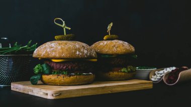 Fasulye, pancar kökü ve vejetaryen peynirli ve turşulu bezelyeli vejetaryen burger. Ev yapımı sağlıklı tarif. Karanlık huysuz stili.