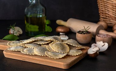 Taze çiğ İtalyan makarnalı ravioli veya mantarlı tortelli, pesto ve ricotta..