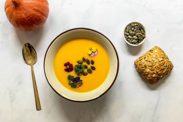 Yenebilir çiçekler, tohum ve taze pişmiş ekmekle sonbahar balkabağı kreması çorbası..