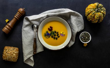 Yenebilir çiçekler, tohum ve taze pişmiş ekmekle sonbahar balkabağı kreması çorbası..