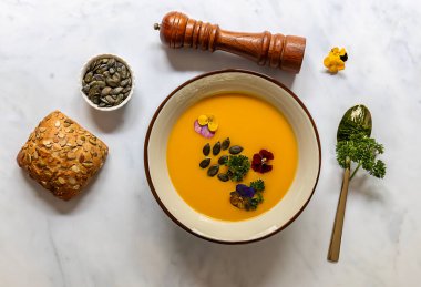 Yenebilir çiçekler, tohum ve taze pişmiş ekmekle sonbahar balkabağı kreması çorbası..