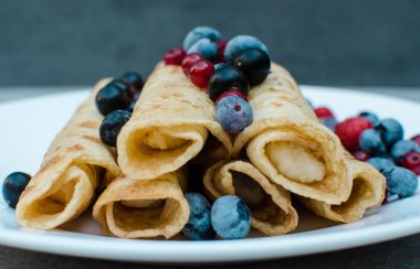 Krepli sabah kahvaltısı, yaban mersini ve ahududu ile süslenmiş taze yaban mersini tabağı, yakın plan gri betondan yapılmış. Sağlıklı kahvaltı kavramı