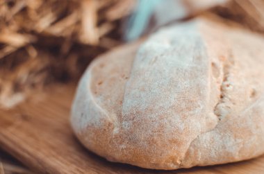 Tahtadaki buğday ekmeğine karşı altın buğday samanı. Doğal zemin. Ekmek, kağıt ve ahşap tahta üzerinde. Taze pişmiş buğday ekmeği. 