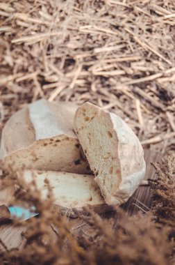 Tahtadaki buğday ekmeğine karşı altın buğday samanı. Doğal zemin. Ekmek, kağıt ve ahşap tahta üzerinde. Taze pişmiş buğday ekmeği. 
