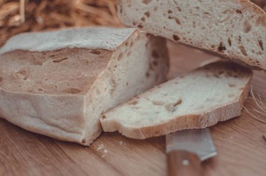 Tahtadaki buğday ekmeğine karşı altın buğday samanı. Doğal zemin. Ekmek, kağıt ve ahşap tahta üzerinde. Taze pişmiş buğday ekmeği. 