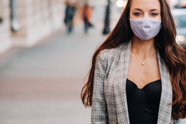 Covid-19 ve Hava kirliliği pm2.5 konsepti. Salgın, sokakta koruyucu maske takan genç bir kadının portresi. Sağlık ve güvenlik kavramını