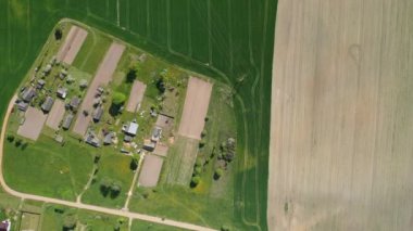 Ekilmiş yeşil bir tarlanın ve Belarus 'ta küçük bir köyün üst manzarası. Köydeki tarımsal tarlalar. Küçük bir köyde tohum ekiyorlar.