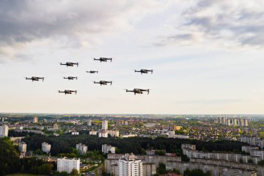Dronlar Minsk şehrinin evlerinin üzerinde uçuyor. Üzerinde insansız hava araçları uçuşan şehir manzarası. Kuadrokopterler şehrin üzerinde uçuyor.