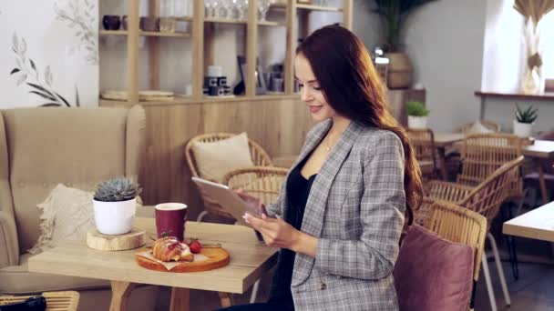 Girl Sits Cafe Looks Tablet Girl Coffee Shop Smiles Distant — Stock Video