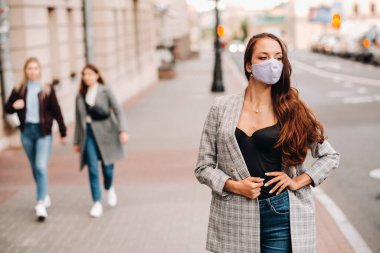 Covid-19 ve Hava kirliliği pm2.5 konsepti. Salgın, sokakta koruyucu maske takan genç bir kadının portresi. Sağlık ve güvenlik kavramını.