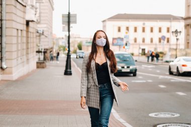 Covid-19 ve Hava kirliliği pm2.5 konsepti. Salgın, sokakta koruyucu maske takan genç bir kadının portresi. Sağlık ve güvenlik kavramını