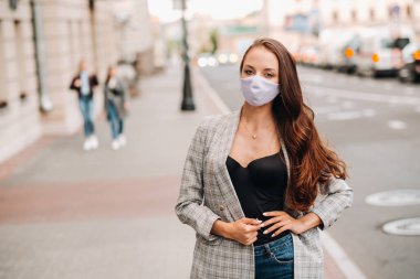 Covid-19 ve Hava kirliliği pm2.5 konsepti. Salgın, sokakta koruyucu maske takan genç bir kadının portresi. Sağlık ve güvenlik kavramını