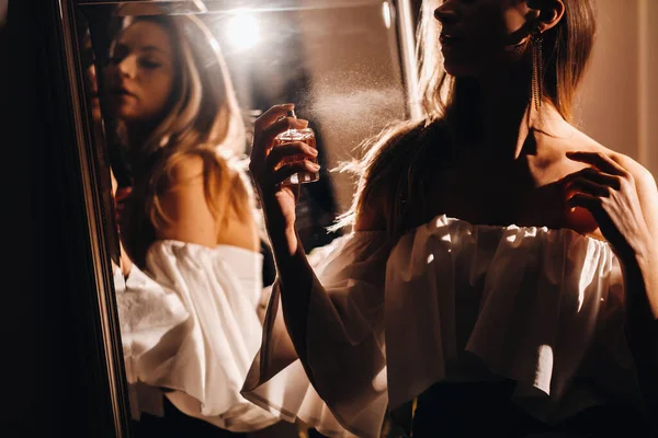 一位身穿带有香水的晚礼服的年轻女子站在家用梳妆台前 女孩在参加宴会前使用香水 — 图库照片